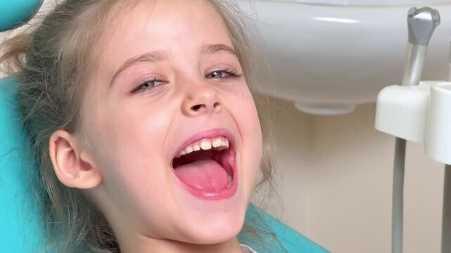 Close-up of little girl opening her mouth wide to the doctor to show her throat. Child is sitting with wide open mouth, with a tongue stuck out, clear view on the uvula and the soft palate
