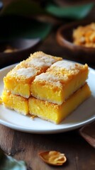 Stack of golden yellow bibingka cake squares on white plate with sugary topping