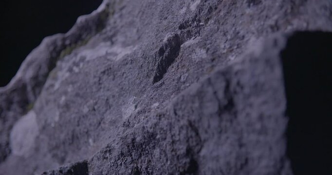 Tilted close-up of a weathered stone at Drombeg Circle, textured and shadowed under shifting light, evoking ritual and mystery.