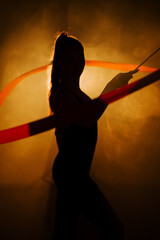 Woman performs rhythmic gymnastics with ribbons in a dramatic setting