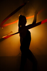 Woman performs rhythmic gymnastics with hoops in a dramatic lighting setting