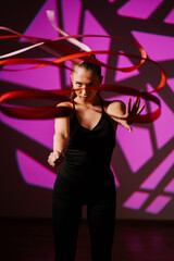 Woman performs rhythmic gymnastics with ribbons in vibrant, colorful setting