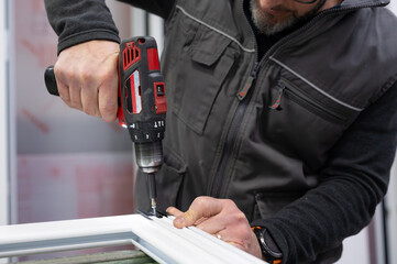 Carpenter using cordless drill assembling aluminum window frame