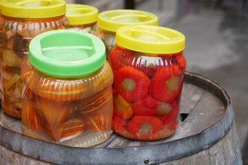 Colorful jars of preserved fruits displayed on a wooden barrel