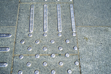 Accessible urban environment: tactile covering of metal elements in the form of dots and stripes installed on pavement tiles. Infrastructure for safe movement of visually impaired and blind people