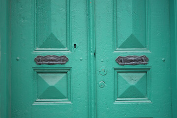 Stunning teal door with intricate handles in an urban setting