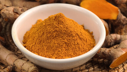 Turmeric powder in a cup and fresh turmeric