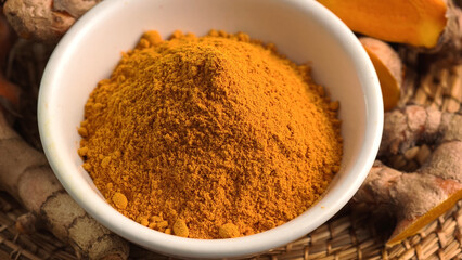 Turmeric powder in a cup and fresh turmeric