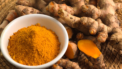 Turmeric powder in a cup and fresh turmeric