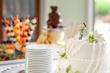 Beautifully Decorated Wedding Cake with Figurines Amidst Celebration Setup