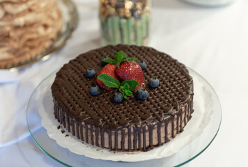 Delicious Chocolate Cake Decorated with Fresh Strawberries and Blueberries on White Plate