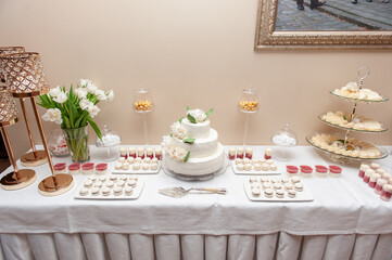 Elegant Wedding Dessert Table With Cake, Sweets, and Floral Arrangements