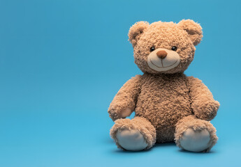 Obraz premium Adorable plush teddy bear sitting against a bright blue backdrop.