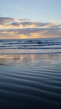Tenerife's stunning sunset casts its final rays over the ocean, with the waves gently lapping the shore, offering a peaceful retreat into nature.