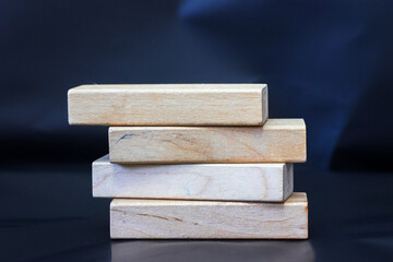 A pile of four wooden blocks on the soft black background.