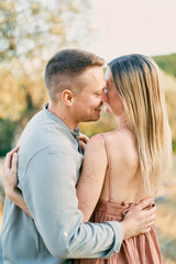 Obraz premium Smiling man hugs woman, touching his nose to her cheek. Back view