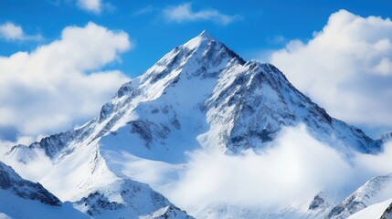 Majestic snow covered mountain peak with clouds against blue sky background