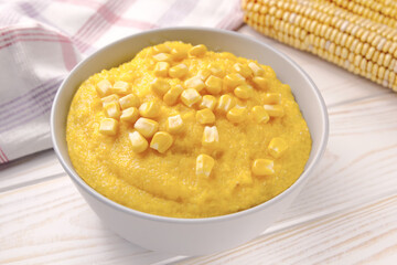 Delicious corn porridge in a bowl on a white wooden table.