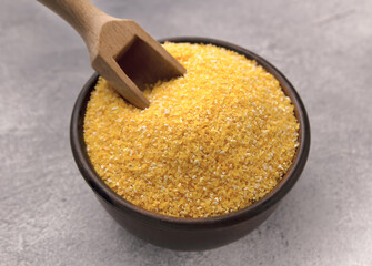 Raw cornmeal in a bowl on a gray tiled table