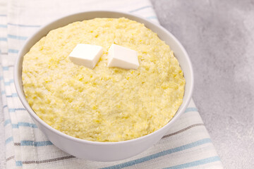 Vegetarian breakfast: millet porridge with butter in a white plate on a gray background