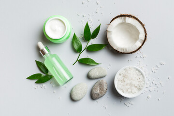 Coconut with jars of coconut oil and cosmetic cream on colored background. Top view. Free space for your text. Natural spa coconut cosmetics and organic treatment concept Coconut Spa composition