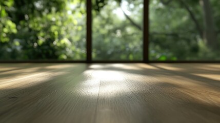 Fototapeta premium Interior view shows sunlight streaming onto a wooden floor through a window overlooking lush green trees.