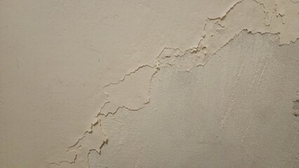 A close-up of a rough, worn-out concrete wall with a gritty texture, featuring cracks and crevices....