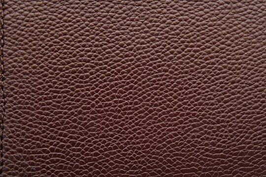 Close-up view of deep maroon textured leather. - Powered by Adobe