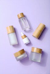 Four frosted glass cosmetic jars and bottles with bamboo lids are arranged