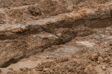 Industrial sand and clay quarry under natural daylight, emphasizing the coarse and uneven structure of the ground. A powerful visual metaphor for extraction, construction.