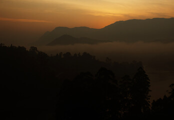 Golden mist blankets mountain silhouettes.
