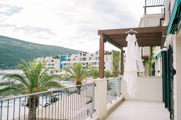 Bride dress hangs on a hanger on the balcony of a hotel by the sea