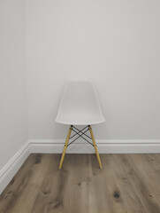A minimalist modern chair against a stark white wall, minimalist style.

