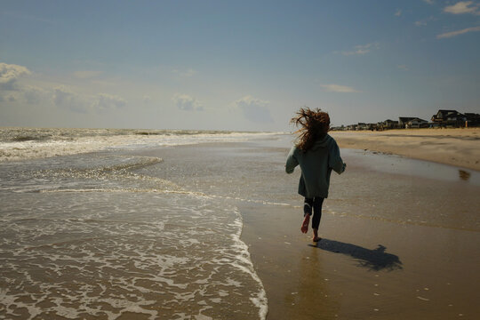 Young girl blonde hair running down beach  Atlantic Ocean