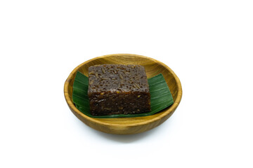 A Homemade traditional cake called wajik ketan gula merah is served on a wooden plate with a banana...