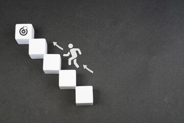 White blocks with an icon of a person climbing stairs gesture, reaching the target in business...