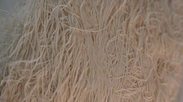 Delicate strands of kadaif are showcased in a lively kitchen, ready to be incorporated into a delicious traditional dessert. The warm lighting enhances the texture of the dough.