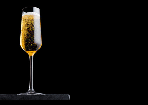Elegant glass of yellow champagne with bubbles on blavk marble board on black background. Space for text