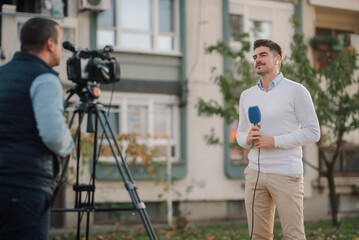 Journalist reporting live news with cameraman recording video outdoors