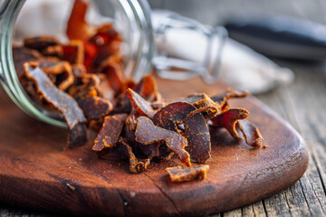 Beef jerky. Dried spiced meat on wooden table.