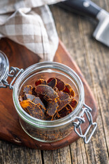 Beef jerky. Dried spiced meat in jar on wooden table.