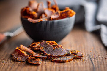 Beef jerky. Dried spiced meat on wooden table.