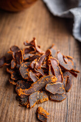 Beef jerky. Dried spiced meat on wooden table.