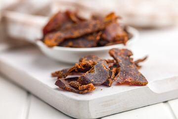 Beef jerky. Dried spiced meat on white table.