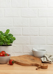 Kitchen utensils, fresh tomatoes, basil plant and mortar with pestle on wooden table