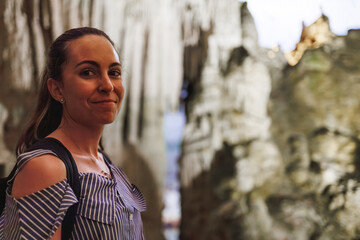 Woman visiting an ancient cave and smiling to the camera, copy space.
