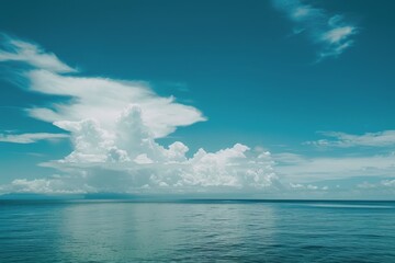 Obraz premium A panoramic view of a tranquil ocean scene with a vibrant blue sky and fluffy white clouds, A serene and vast blue backdrop