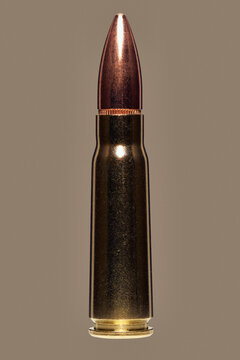 Close up studio shot of 7.62 x 39mm bullet used with AK-47 on brown background

