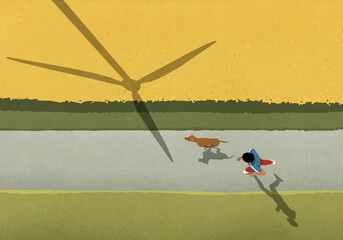 View from above man and dog jogging on path along field with wind turbine shadow
