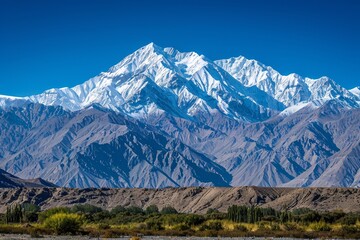 Fototapeta premium Majestic snow-covered mountains rise against a clear blue sky, showcasing the breathtaking beauty of the Himalayas, Snow-capped mountains under a clear blue sky